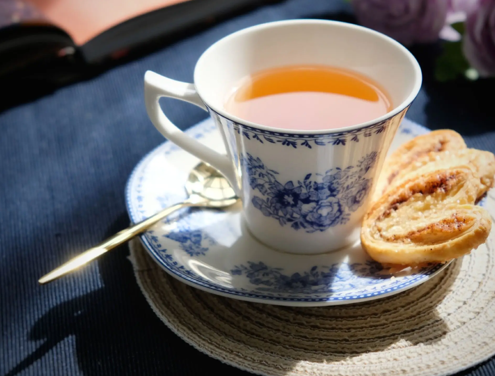 Blue and white teacup with tea and pastries