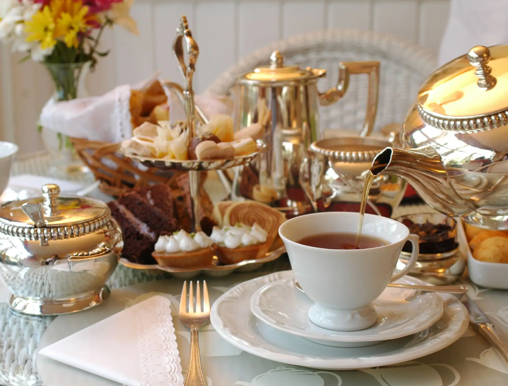 Afternoon tea with silver teapot pouring tea