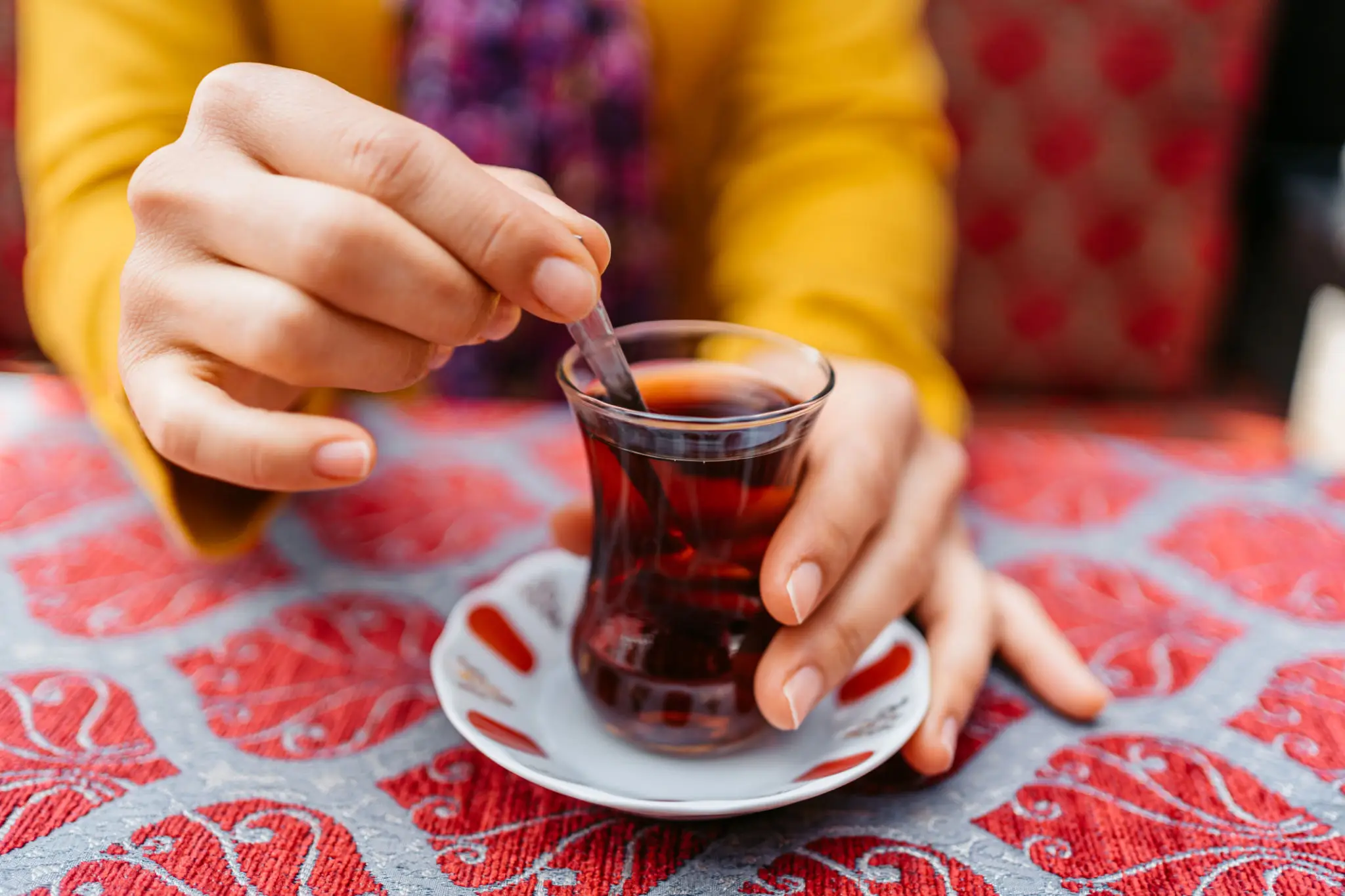 Hand stirring Turkish tea in tulip glass
