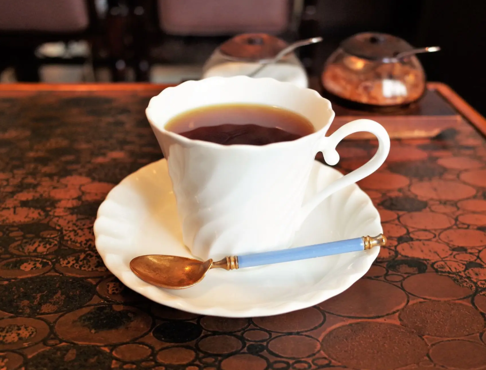 White teacup of tea with blue spoon