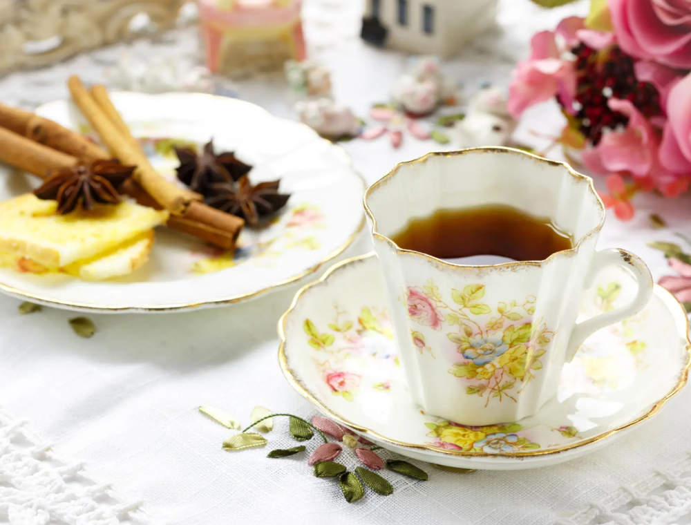 Floral teacup with tea, cinnamon, cookies