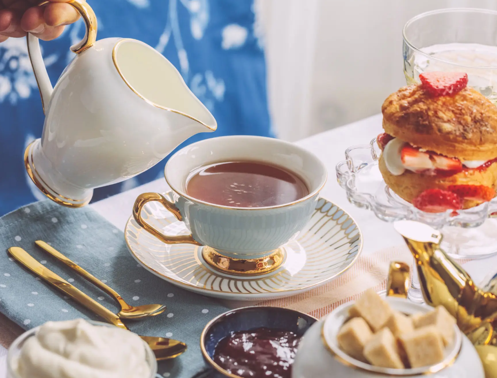 Pouring tea into porcelain cup with scones